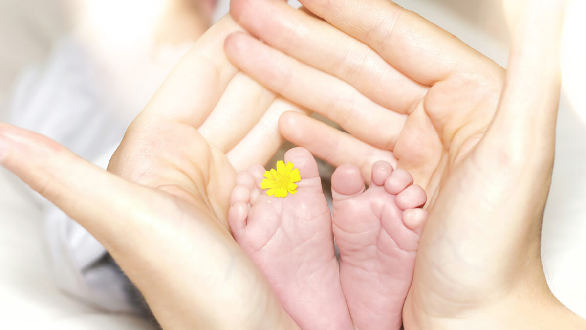 A mother cupping her babies little feet in her hands.